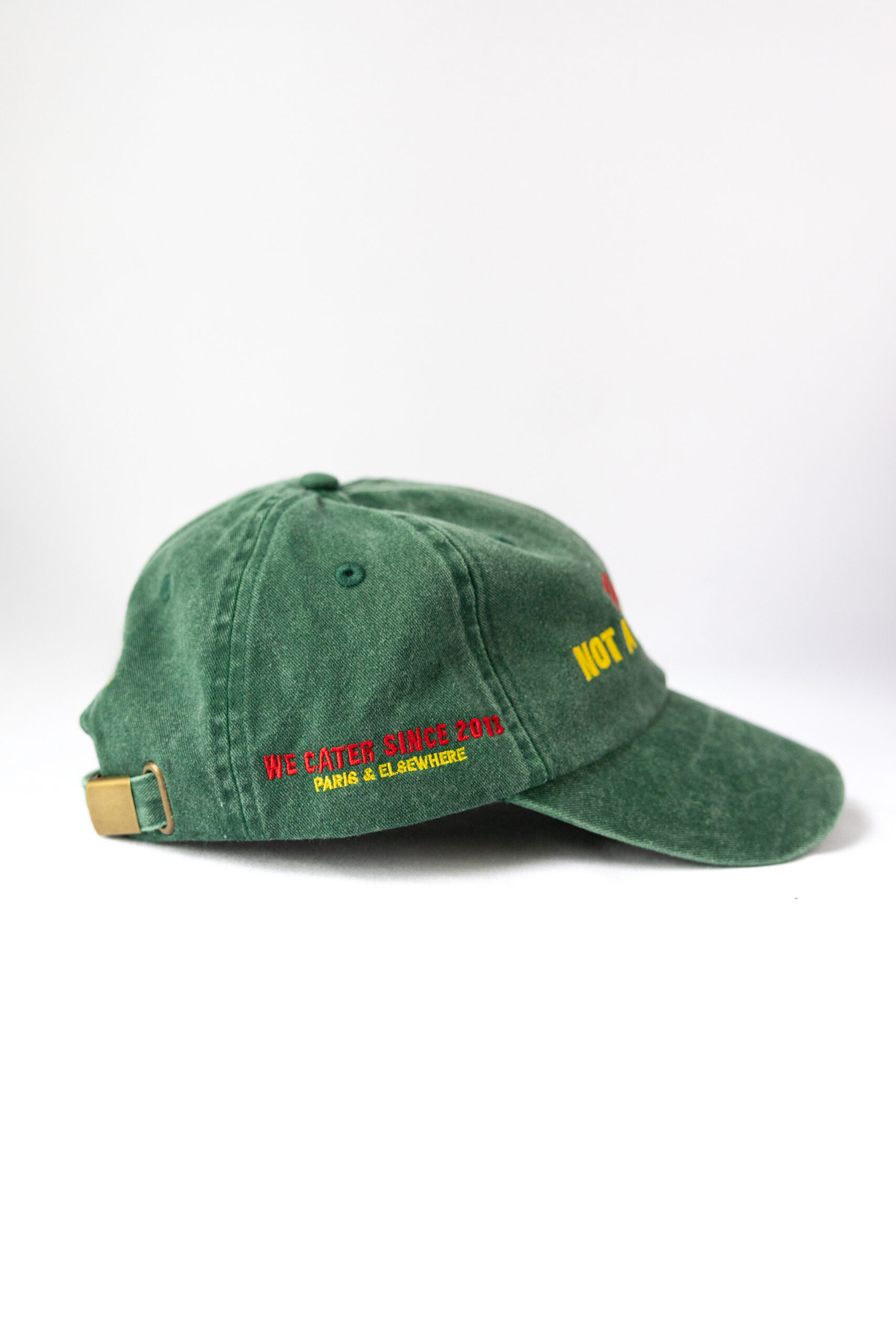 Le visuel montre une casquette verte de vue de côté. Le style vestimentaire est décontracté et cool et l'on voit une broderie jaune et rouge indiquant « We cater since 2013. Paris & Elsewhere. », un clin d'oeil à l'activité du traiteur Chicken Bacon Lettuce.