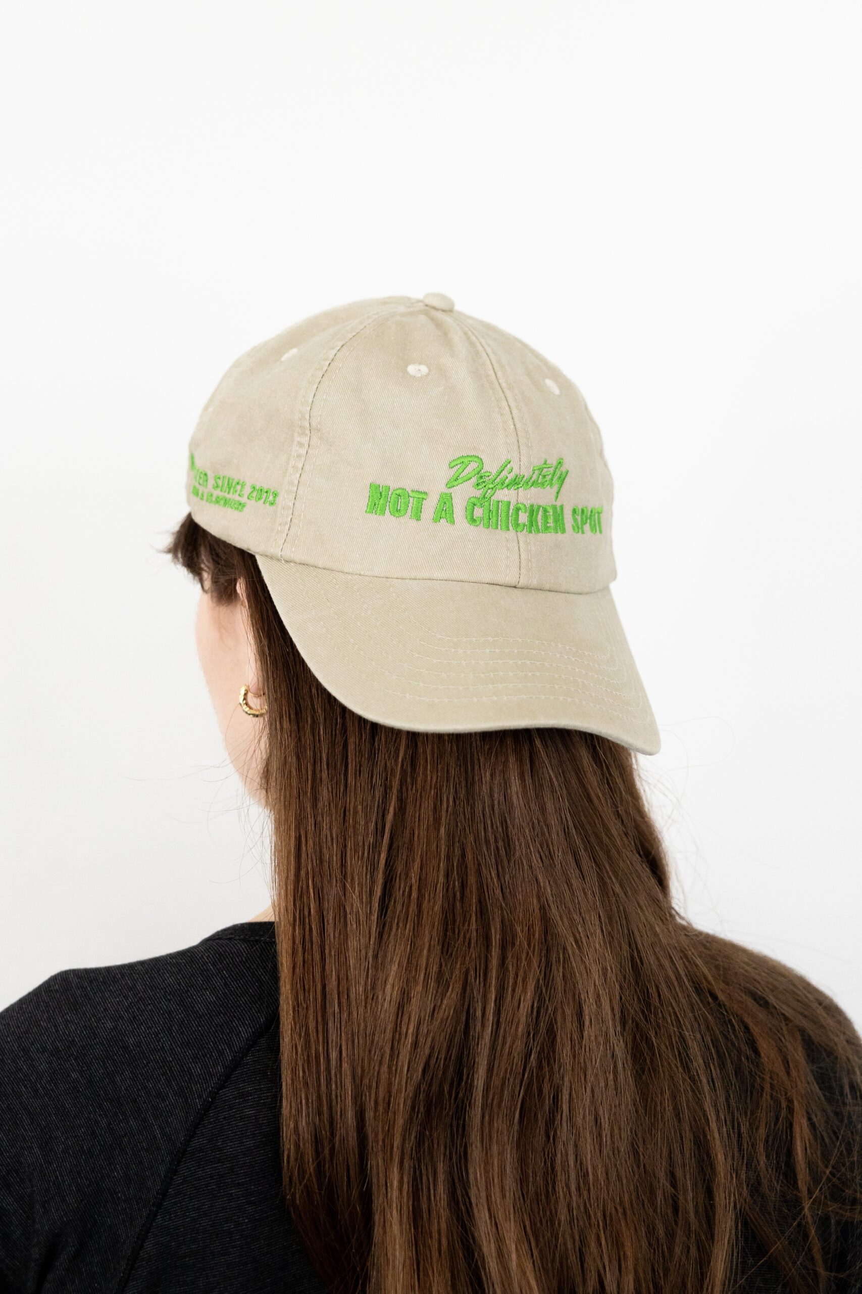 Le visuel montre quelqu’un de dos. La personne porte une casquette à l’envers. La casquette est beige. Le style vestimentaire est décontracté et cool et l'on voit une broderie verte sur le devant indiquant « Definitely Not a Chicken Spot », un clin d'oeil au nom du traiteur Chicken Bacon Lettuce.
